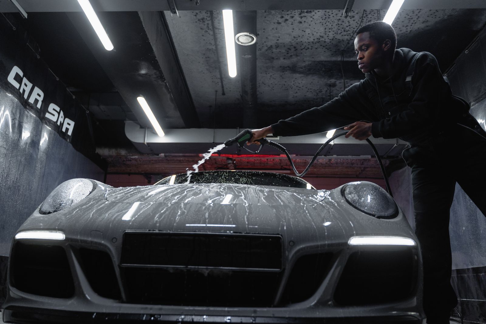 Detailer carefully pressure-washing a sports car